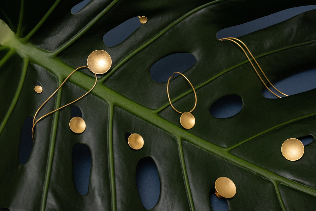 Gold-plated disc jewerly on a big green leaf