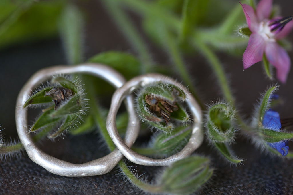 Organic wedding ring set in silver with plants in the background