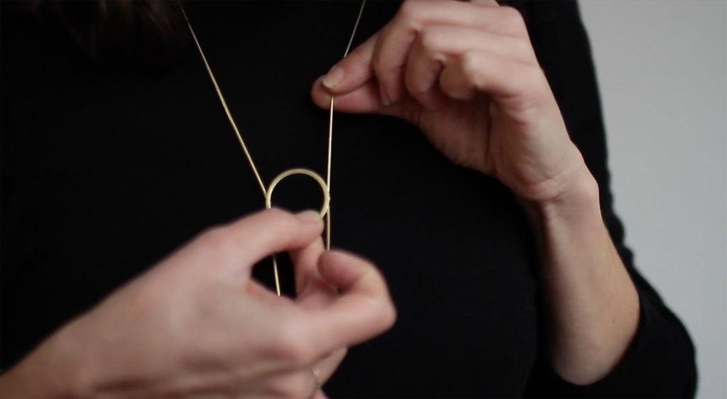 Flowring necklace adjustment demonstration. Upclose of two hands adjusting the necklace 